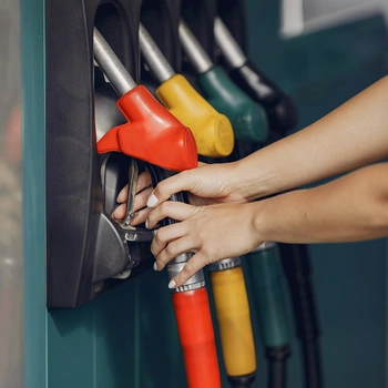 Image of a fuel filling station with a worker holding the fuel pump