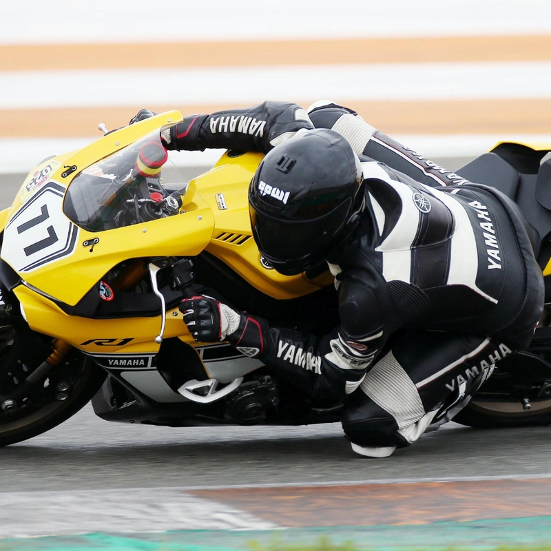 A racer in black track suit riding yellow color motorcycle and knee dragging on the corner